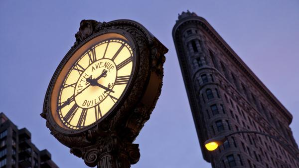 Fifth Avenue Clock in front of the Flatiron Building in New York City. Fifth Avenue Clock with the Flatiron Building at the background in New York City.